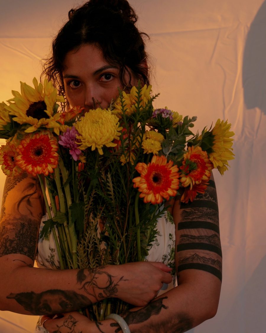 Beca holding a big bouquet of sunflowers and gerbera daisies